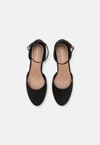Černé semišové kotníkové sandály s rounded toe, hladkým vnitřním podšitím a zlatým přezkovým detailem na pásku. Ploské podešve.