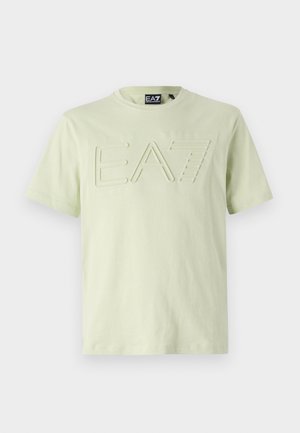 Maglietta a maniche corte verde chiaro con logo "EA7" in rilievo sul davanti, realizzata in un tessuto morbido e dalla texture liscia. Design semplice.