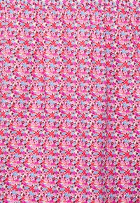 Tecido com padrão floral apresentando uma mistura de flores rosas, vermelhas e azuis sobre um fundo rosa claro. O material parece suave e leve.