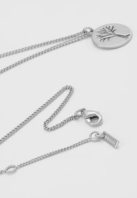 Collier en argent avec une pendentif ovale au design d'arbre, un fermoir à homard et une petite étiquette gravée "Pilgrim."