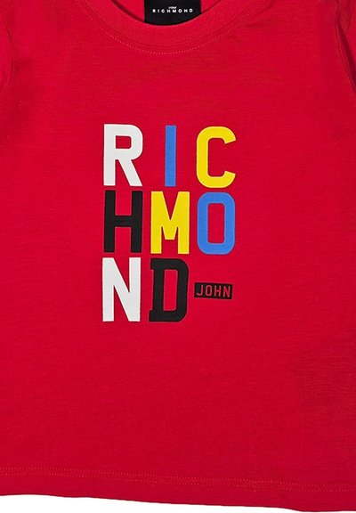 T-shirt rossa in cotone con testo audace in bianco, nero, giallo, blu e rosso. Design con girocollo e maniche corte.