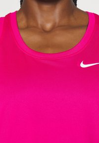 Magenta sportovní tílko s kulatým výstřihem, hladkou texturou a bíl�ým logem Nike na levé horní straně.