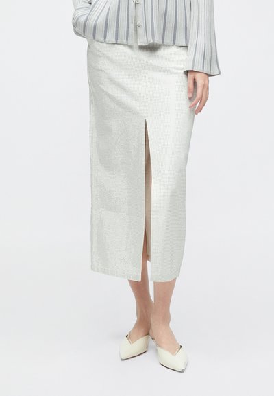 White textured pencil skirt with a front slit, made from a lightweight fabric. Paired with light-colored, pointed-toe flats.