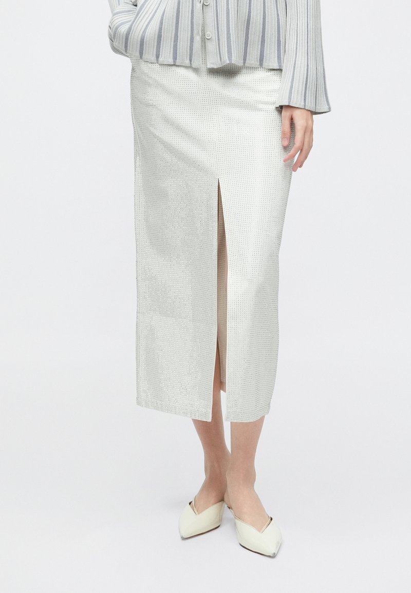 Λευκή υφασμάτινη μολυβοθήκη με χαραγμένη υφή και με σκίσιμο στο μπροστινό μέρος, φτιαγμένη από ελαφρύ ύφασμα. Συνδυασμένη με ανοιχτόχρωμες μπαλαρίνες μυτερές στη μύτη.