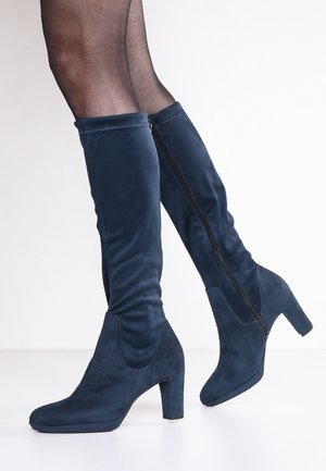 Navyblauwe kniehoge laarzen van zacht suede, met een blokhak, een rits aan de zijkant en een aansluitend, slouchy ontwerp. Gladde textuur, minimale details.