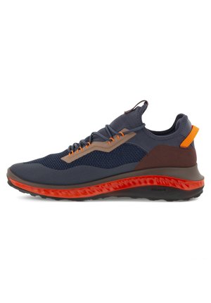 Chaussure de sport basse avec tige en mesh bleu marine, accents marron et beige, languette et bordure de semelle orange vif, et semelle extérieure en caoutchouc noir.