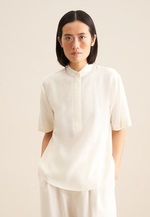 Crème-kleurige blouse met korte mouwen en een staande kraag, voorzien van een knoopsluiting en gemaakt van een gladde, lichtgewicht stof.