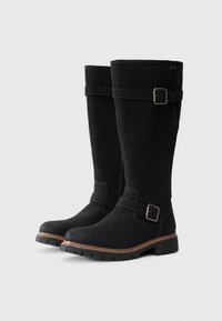 Schwarze Wildleder-Stiefel bis zum Knie mit flacher Gummisohle, Schnallenakzent und Kontrastnähten. Abgerundete Zehenpartie und glatte Textur.