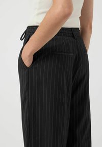 Zwarte pinstripe broek met een relaxte pasvorm, met zijzakken, een verstelbare tailleband en een gladde textuur.