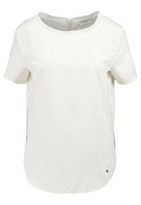 Blusa blanca de manga corta hecha de tela suave, con cuello redondo, aberturas laterales y cremallera en la parte trasera. Presenta un sutil logotipo cerca del dobladillo.