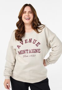 Svetlobežový mikina s nápisom "AVENUE MONTAIGNE Paris 1850" v burgundskej farbe. Má okrúhly výstrih a voľný strih.