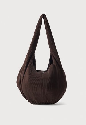 Sac porté à l’épaule en tissu côtelé marron foncé, avec de longues anses, sur un fond clair uni.