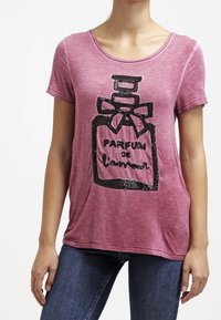 Vínová krátká trička s krátkým rukávem s černou flitrovou grafikou parfémové lahvičky a textem "PARFUM de l'amour." Měkká, opotřebovaná textilie.