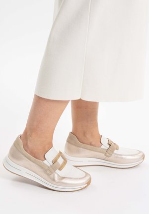 Beige und weiße Slipper mit strukturierter Oberfläche, ausgestattet mit zwei dekorativen Riemen, einer gepolsterten Sohle und einem runden Zehendesign.