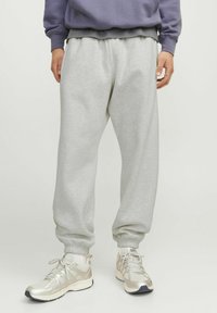 Gray sweatpants made of soft cotton blend, featuring an elastic waistband, ribbed cuffs, and a relaxed fit. Styled with light sneakers.