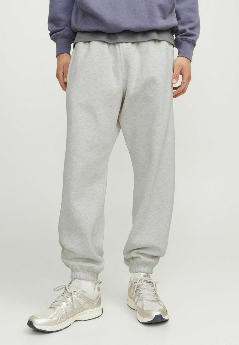 Gray sweatpants made of soft cotton blend, featuring an elastic waistband, ribbed cuffs, and a relaxed fit. Styled with light sneakers.