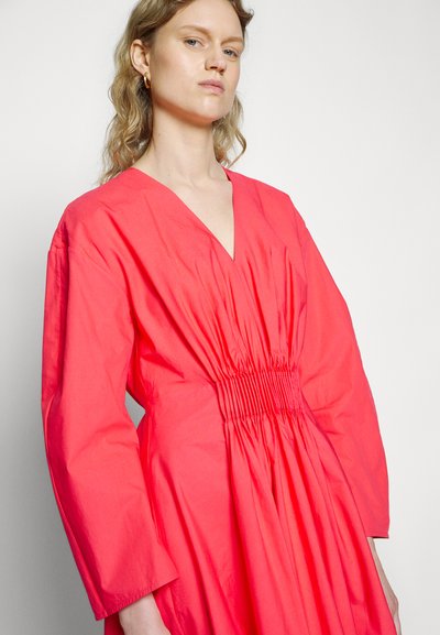 Vestido coral rosa com decote em V, mangas longas e detalhe de cintura franzida. Feito de um tecido leve com uma superfície ligeiramente texturada.