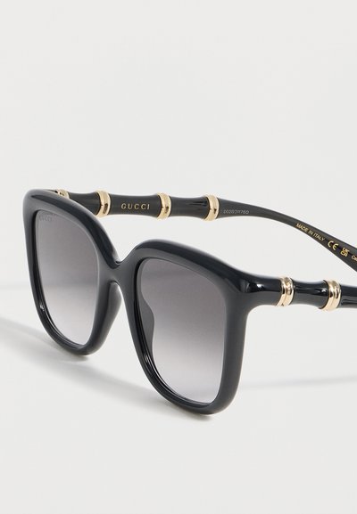 Μαύρα υπερμεγέθη τετράγωνα γυαλιά ηλίου με φακούς διαβάθμισης και χρυσές λεπτομέρειες σε στυλ μπαμπού στους βραχίονες, επώνυμα Gucci, κατασκευασμένα στην Ιταλία.