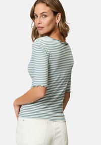 Stribede bomulds t-shirt i lyseblå og hvid, med en scalloped halsudskæring og korte ærmer med let udfladede kanter.