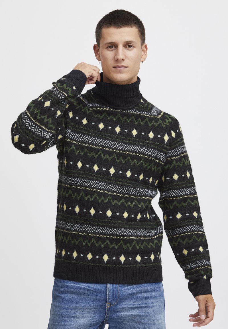 Pulover negru tricotat cu guler înalt, având modele geometrice în verde, galben și alb. Material texturat și design ajustat.