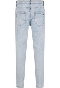 Jean en denim bleu clair vu de dos avec deux poches arrière, passants de ceinture et une coupe fuselée.