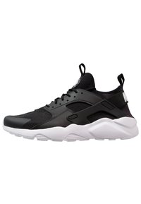 Black athletic shoe with mesh and synthetic materials, white midsole, distinctive heel cutout, and black accent details.