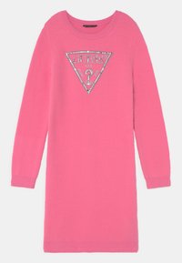 Abito maglione rosa realizzato in tessuto morbido e testurizzato. Presenta un logo triangolare argentato con la scritta "GUESS?" al centro. Maniche lunghe e scollo rotondo.