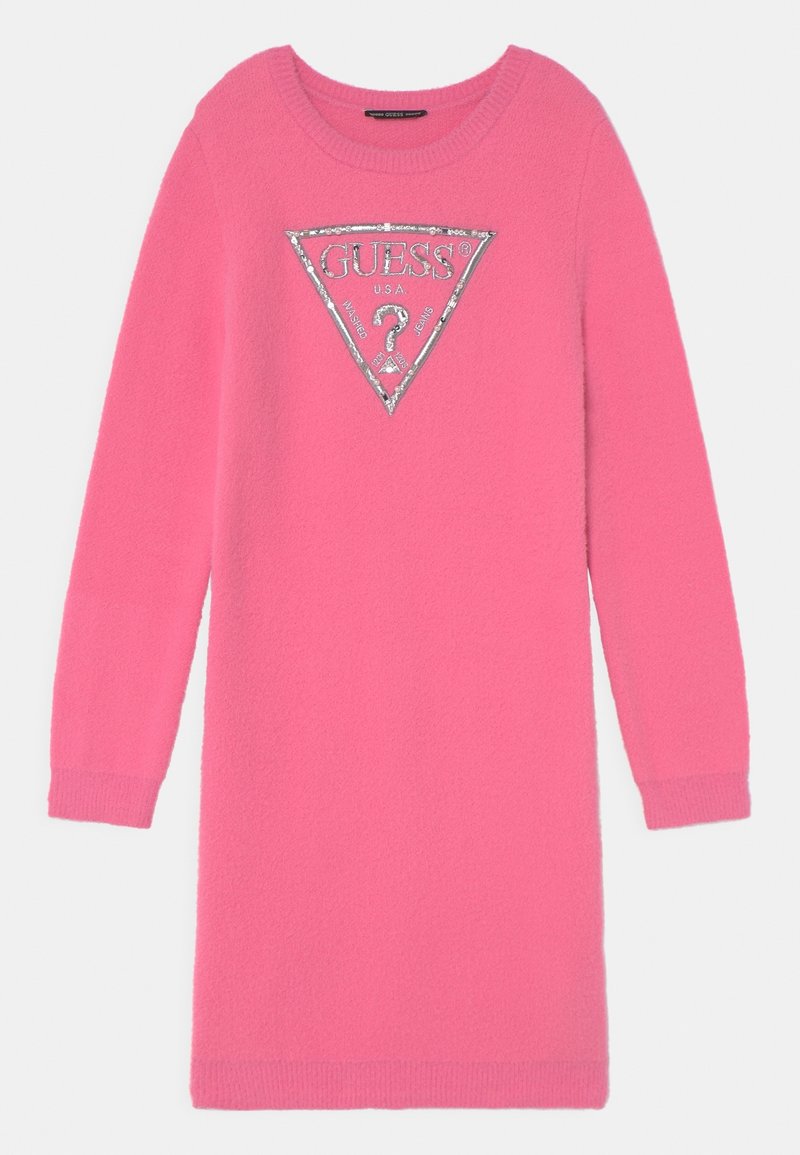 Abito maglione rosa realizzato in tessuto morbido e testurizzato. Presenta un logo triangolare argentato con la scritta "GUESS?" al centro. Maniche lunghe e scollo rotondo.