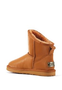 Tanfarbene Lederstiefelette mit flauschigem Innenfutter, runder Zehenform und einem leichten Absatz. Enthält ein markiertes Metallelement an der Seite.