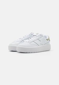 Hvit lær sneakers med en jevn tekstur, som har rund tå, tykk hvit såle, og et subtilt lys grønt tillegg på hælen.