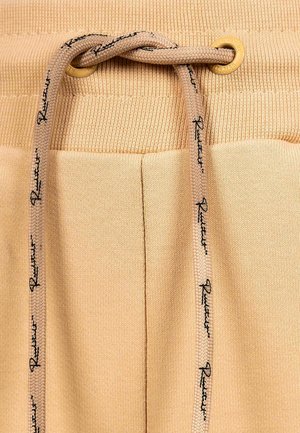 Beige joggers van textuurstof, met een geribbelde tailleband, een trekkoord met logoaccenten en twee zijzakken.
