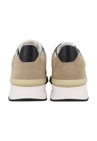 Beige Wildlederschuhe mit schwarzen Lederakzenten, weißer Zwischensohle und grünen Details. Gepolsterter Innenraum und strukturierter Ferseneinsatz.