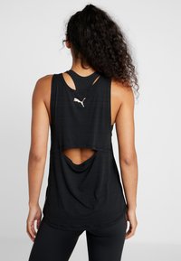 Svart atletisk linne med skär bak, tillverkat av lättviktsmaterial. Har en rund halsringning och Puma-logotypen på övre delen av ryggen.