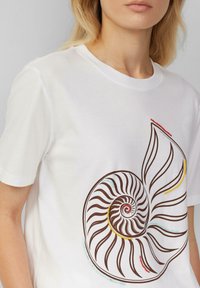 Witte katoenen t-shirt met een bruine spiraalschelp grafiek met kleurrijke accenten in rood, geel en blauw, in een relaxed-fit ontwerp.