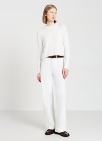 Weißer kabelgestrickter Pullover, entspannte Passform; kombiniert mit hochgeschnittenen weißen weit geschnittenen Jeans und braunem Gürtel; strukturierter Stoff und schlichtes Design.