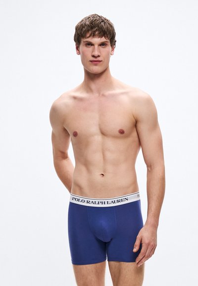 Boxerky námorníckej modrej farby s bielym elastickým pásom s logom "POLO RALPH LAUREN". Vyrobené z mäkkej, elastickej látky pre pohodlie.