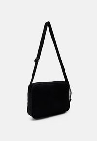 Černá crossbody taška s texturovanou přední částí, hladkými boky a nastavitelným popruhem. Disponuje zipovým uzávěrem a minimalistickým designem.