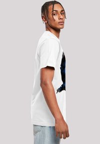 White cotton t-shirt featuring a blue and black graphic design. Short sleeves and a round neckline. Loose fit. Plain back.
