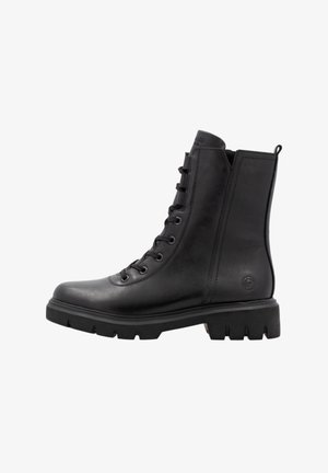 Czarny skórzany trekkingowy but militarny z grubą, ryflowaną podeszwą i pętelką z tyłu, widziany z profilu na białym tle.