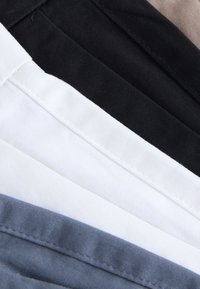 Stalen van katoenen stoffen in vijf horizontale lagen: zwart, wit, licht beige, donkergrijs en lichtblauw, met een gladde textuur en gelijkmatige stiksels.