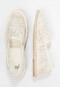 Espadrilles en dentelle avec un design ouvert, de couleur crème, avec un motif floral texturé et des semelles en jute tissé. Style simple à enfiler.