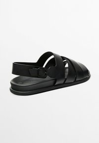 Black sandals made from smooth synthetic material, featuring multiple wide straps and a back buckle for secure fitting. Flat sole.