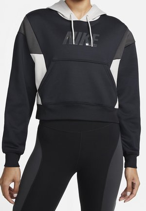 Personne portant un sweat à capuche court Nike noir et gris avec poche avant et des leggings noirs avec des panneaux latéraux gris.