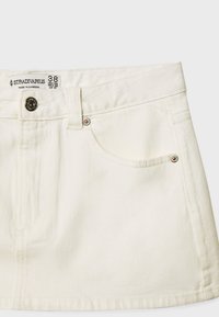 Bela denim krila z teksturiranim zaključkom, s sprednjim žepom, gumbnim zapiranjem in subtilnimi šivnimi detajli ob robu.