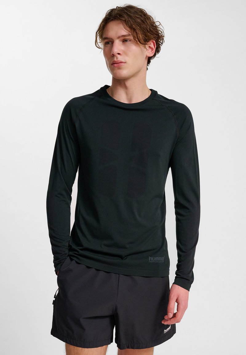 Zwarte sportshirt met lange mouwen van rekbare stof, met een textuurlogo en naadloos ontwerp, gecombineerd met zwarte shorts.