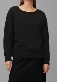Schwarzer Pullover mit rundem Ausschnitt, langen Ärmeln und gerippten Bündchen. Hergestellt aus einem weichen Material und mit einem lässigen Schnitt. Eignet sich gut zum Schichten.