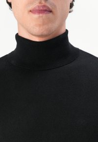 Schwarzer Strickrollkragenpullover mit geripptem Muster. Bietet eine taillierte Passform und minimale Markenkennzeichnung auf der linken Brustseite.