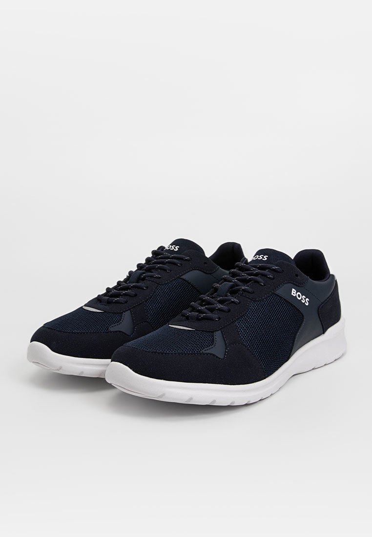 Baskets en maille marine et synthétique lisse avec semelle extérieure blanche, présentant des lacets et un accent logo sur le côté pour le détail de marque.