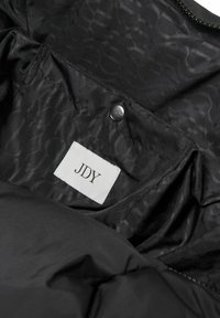 Unutrašnjost crne podstavljene jakne s glatkom teksturom, suptilnim uzorkom logotipa i ušivenom oznakom s natpisom "JDY." Vidljivi detalj s dugmetom na kopčanju.