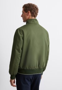 Green bomber jacket with a high collar and elastic cuffs, featuring a smooth texture and a fitted waistline.